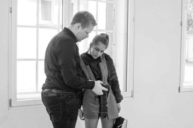 Fashionshooting, Fotograf zeigt Model ein Foto auf dem Kameradisplay, Schwarz-Weiß,