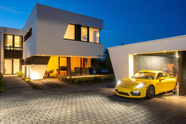 Architekturaufnahme zur blaue Stunde, modernes weißes Haus, Garage mit gelben Porsche