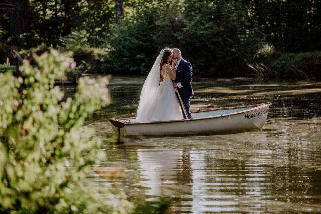 Hochzeit, Portrait, Outdoor, Brautpaar steht in Ruderboot und küsst sich