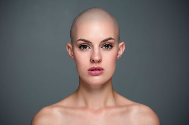 Portrait, Frau mit abrasierten Haaren und ernstem Blick, Nahaufnahme