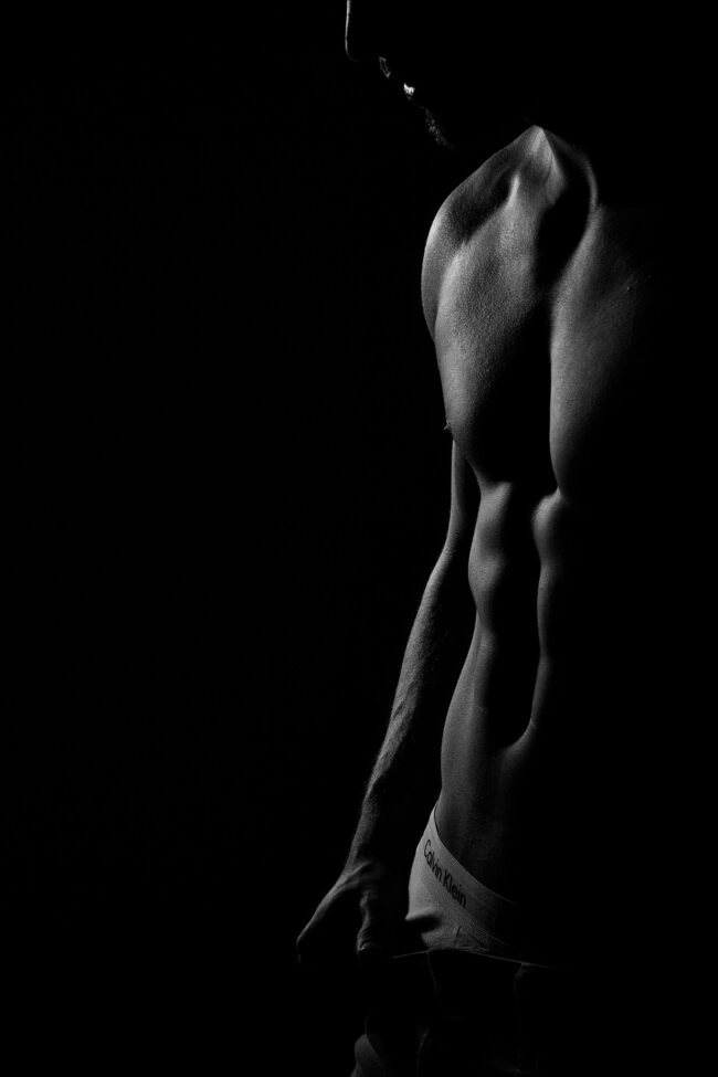 Sensual, Bodypart Brust und Bauchmuskeln Mann, auf schwarzem Hin bergrund, dunkle Beleuchtung, Schwarz-Weiß