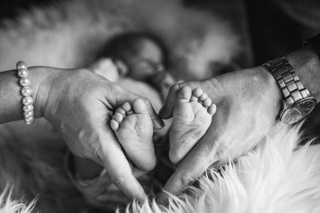 Familie, Hände der Eltern umfassen die fuße des Babys und bilden somit ein Herz, Detailaufnahme, Schwarz-Weiß