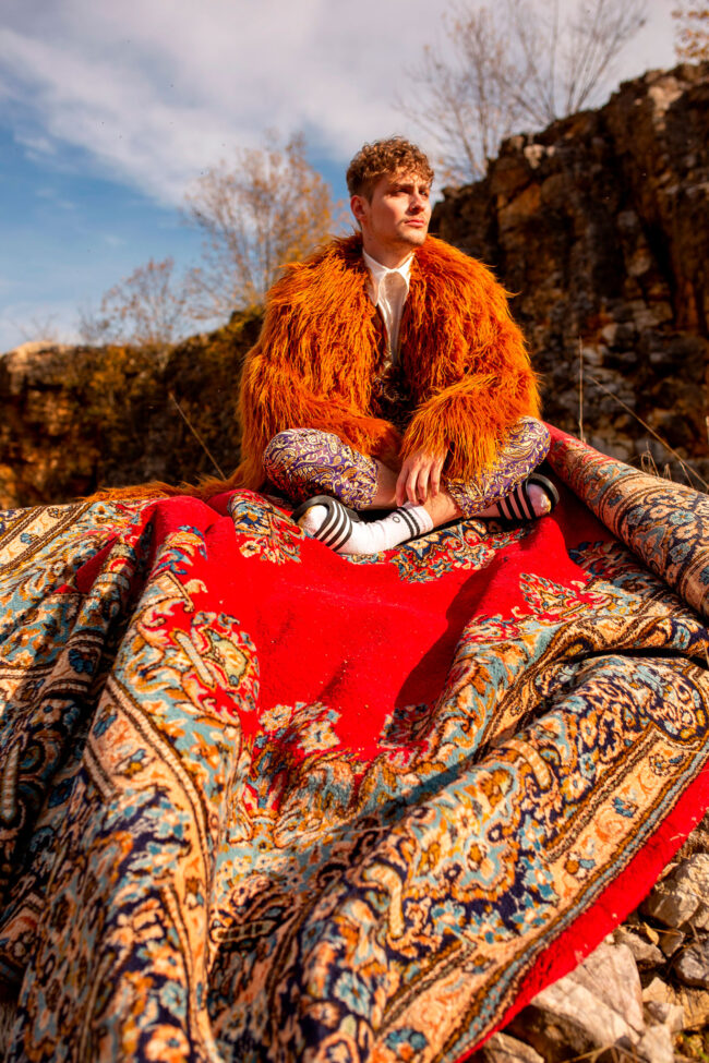 Fashion, Model mit fransigem Oberteil sitzt auf einem Teppich, Outdoor, Hochformat