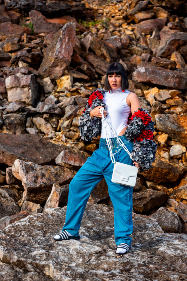 Fashion, Model in Weiß-blauem Outfit, steiniger Hintergrund, Hochformat