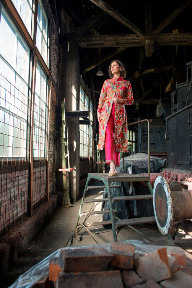 Fashion, Model in besticktem Oberteil auf einer Treppe, vor industriellem Hintergrund, Hochformat