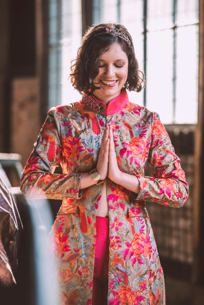 Fashion, Model in besticktem Oberteil legt Hände zusammen, vor industriellem Hintergrund, Hochformat