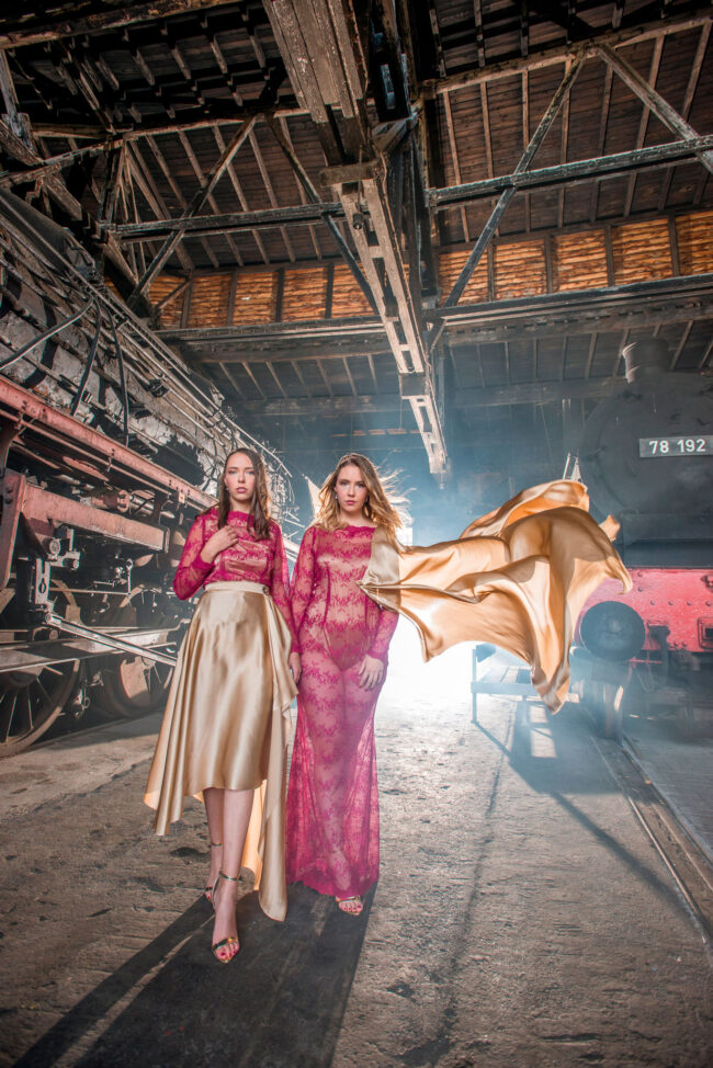 Fashion, 2 Models in bestickten Kleidern tragen beige Tücher, industrieller Hintergrund, Hochformat