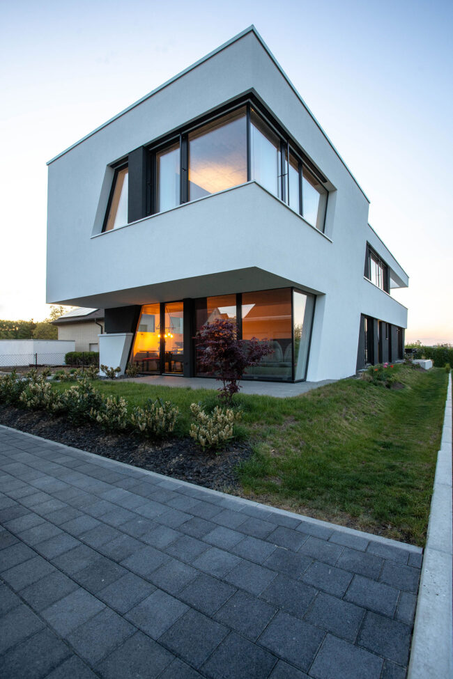 Architektur, modernes weißes Haus mit großen Fensterfronten, umliegender Garten mit Rasenfläche