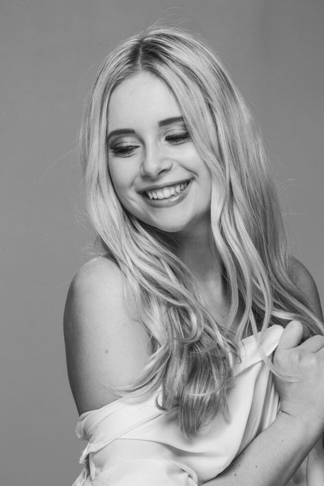 Portrairt, junge Frau lächelnd, mit weißem Hemd über den Schultern, Nahaufnahme, Schwarz-Weiß