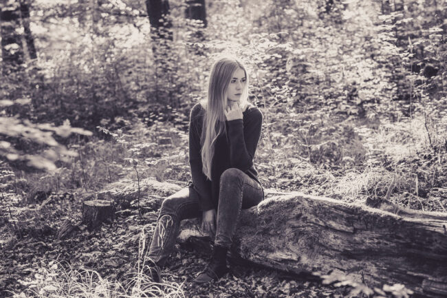 Portrait, Outdoor, Junge Frau sitzt auf einem Baumstamm, Schwarz-Weiß