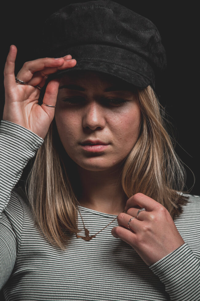 Portrait, junge Frau mit Kappe und gestreiftem Pullover