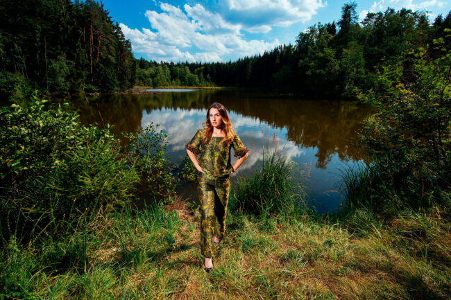 Portrait, Model in grünem Zweiteiler in grüner Natur vor See stehend, Ganzaufnahme, Querformat