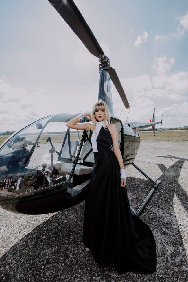 Fashion, Model schwarz weißem Kleid, ärmellos und weißen Manschetten vor Propellerflugzeug, Ganzaufnahme, Hochformat