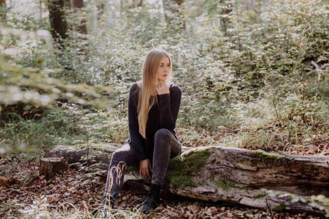 Portrait, Outdoor, Junge Frau sitzt auf einem Baumstamm