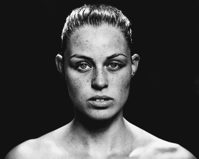 Portrait, junge Frau mit nassem zurückgebundenem Haar schaut ernst in die Kamera, Schwarz Weiß