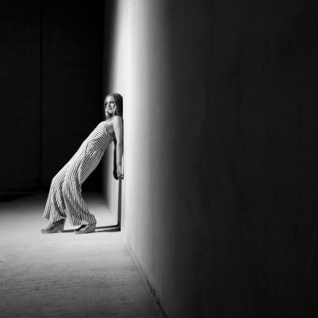 Portrait, Frau lehnt sich im Hohlkreuz gegen Wand, Schwarz Weiß, Ganzaufnahme