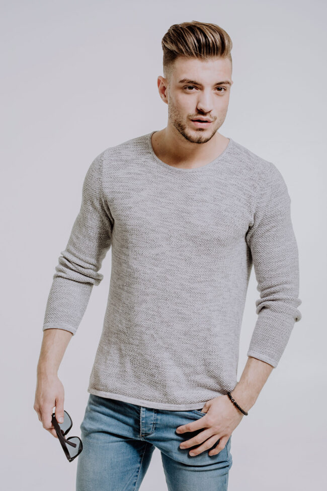 Portrait, junger Mann in Jeans und Pullover mit Brille in der Hand, Halbaufnahme