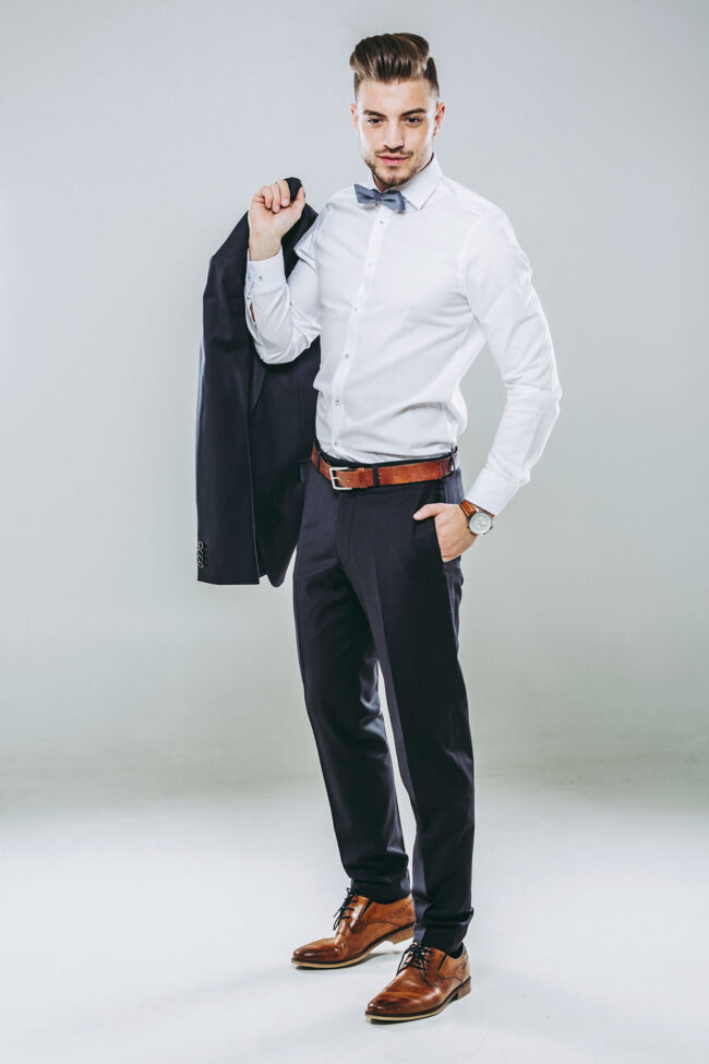 Portrait, junger Mann schwingt Anzugsjacke über die Schulter, Ganzaufnahme