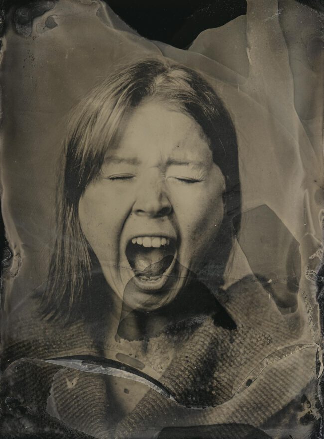 Nassplatte, Schwarz-Weiß, Portraitaufnahme von junger Frau die mit geschlossenen Augen schreit.