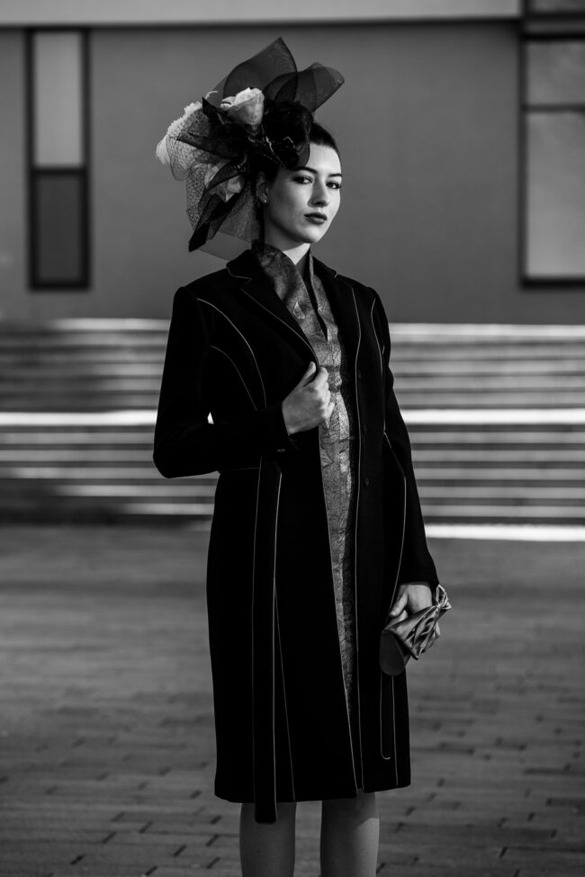 Fashion, Model mit schwarzem knielangen Mantel und einem Großen mit Blumen und Tüll verzierten Hut, Halbbild, schwarz-weiß