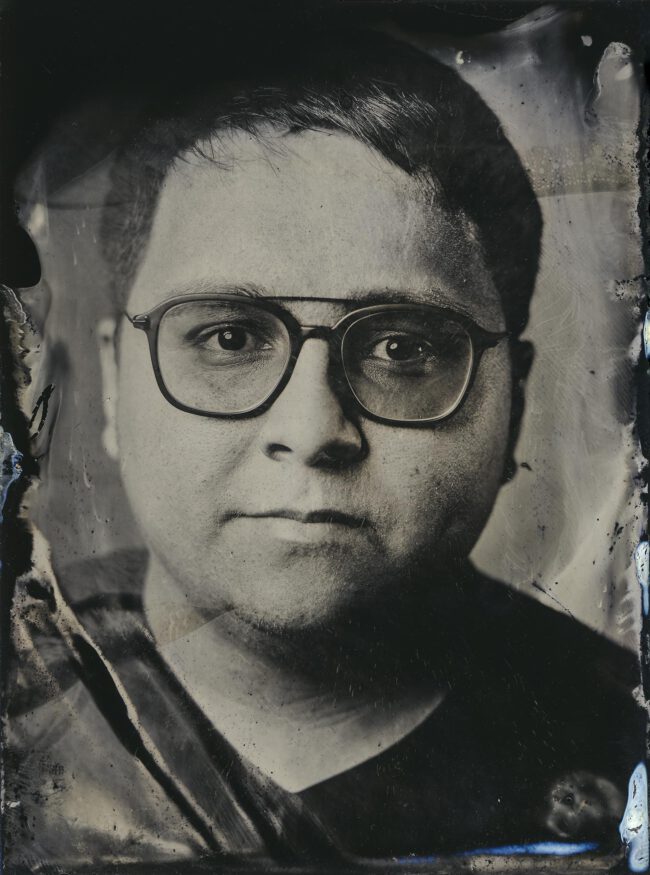 Nassplatte, Schwarz-Weiß, Portraitaufnahme von jungen Mann mit dunklen kurzen Haaren und schwarzer Brille