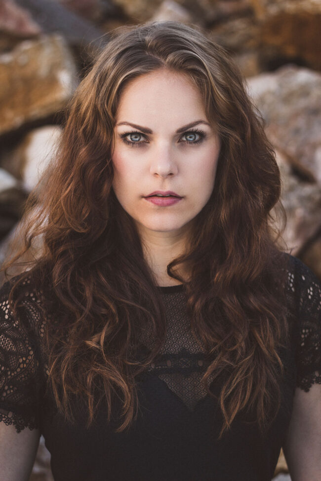 Protrait, Frau mit schwarzem Spitzenoberteil schaut ernst in die Kamera, Halbportrait