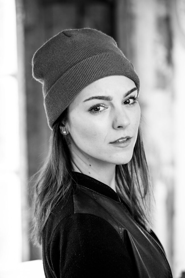 Portrait, Frau mit Mütze und dunkler Jacke schaut ernst in die Kamera, Nahaufnahme, Schwarz-Weiß