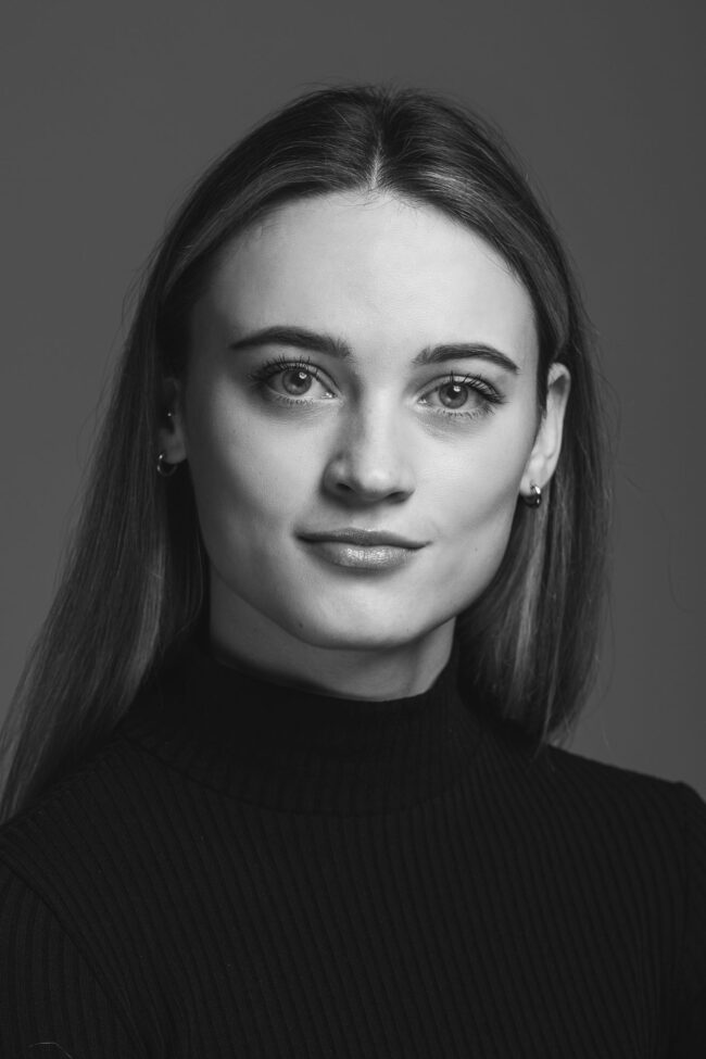 Portrait, Frau mit schwarzem Rollkragenpullover vor grauem Hintergrund, Nahaufnahme, Schwarz-Weiß