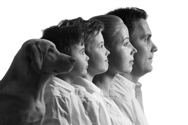 Familie, jede Person im Profil, voreinander aufgereiht, mit Hund, vor weißem Hintergrund, Schwarz-Weiß