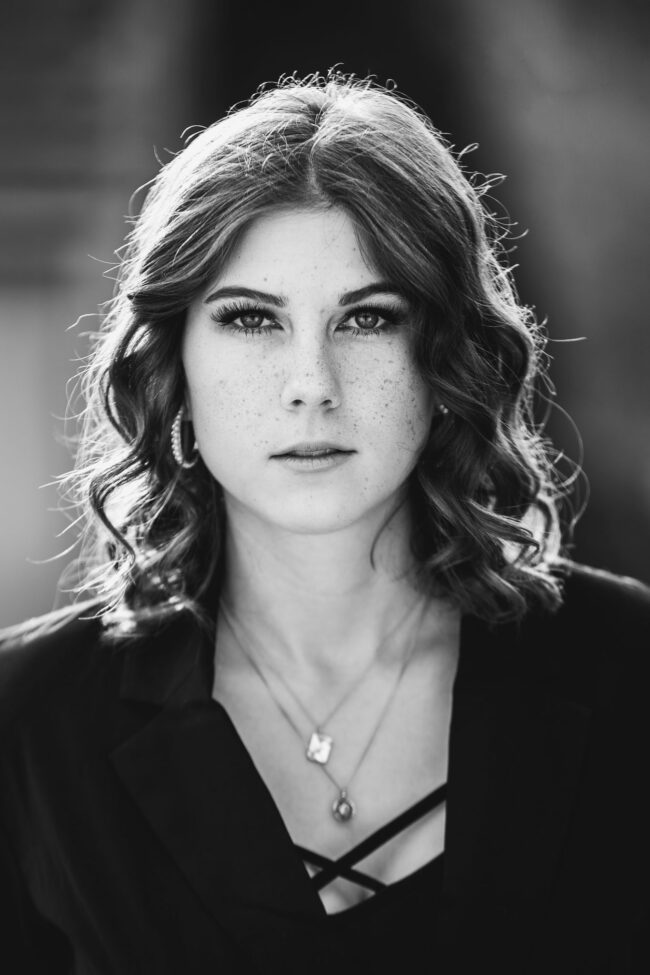 Protrait, Frau mit schwarzem Oberteil schaut neutral in die Kamera, Halbportrait, Schwarz-Weiß