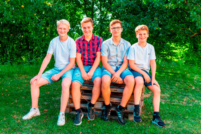 Familienshooting, vier Jungen sitzen auf Holzpaletten, Outdoor