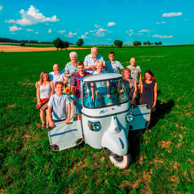 Familienshooting, Familie steht in und um ein kleines Auto, Outdoor