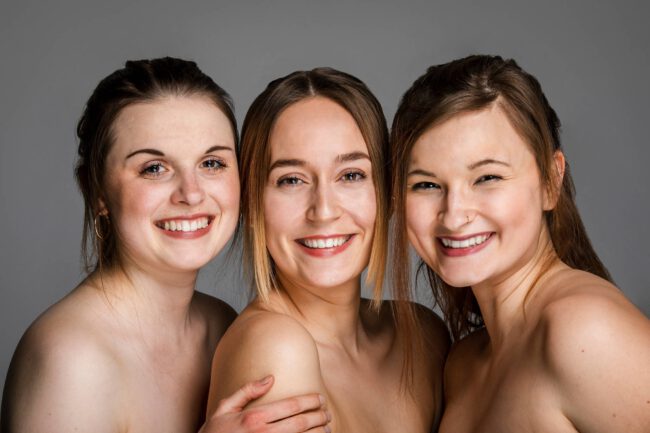 Freundschaftsshooting, drei junge Frauen stehen eng beieinander und lachen in die Kamera, Nahaufnahme