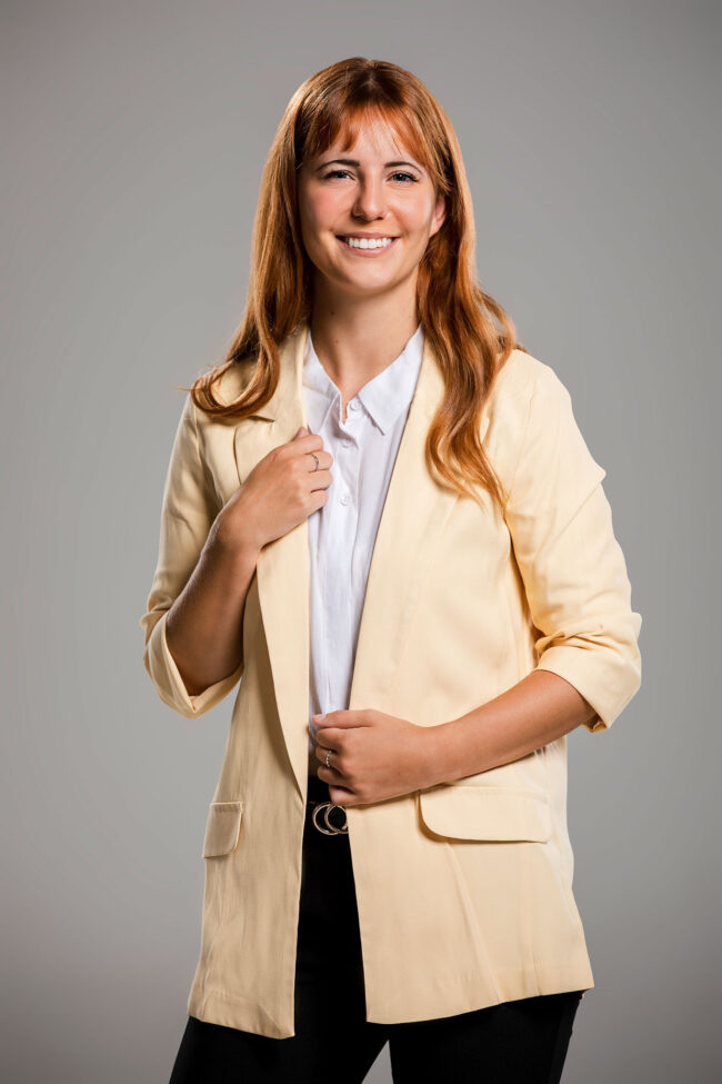 Business Portrait, rothaarige junge Frau in Schwarzer Hose, weißer Bluse und Blazer mit iPad in der Hand, Nahaufnahme, grauer Hintergrund