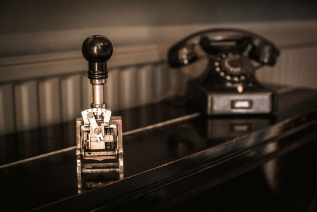 Dekoration, altes Stempelgerät, schwarzes Telefon mit Wählscheibe im Hintergrund
