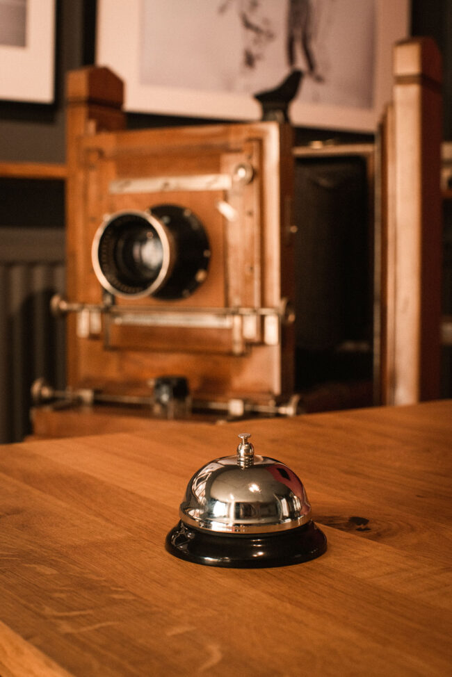 Detailaufnahme, silberne Klingel, im Hintergrund alte Kamera