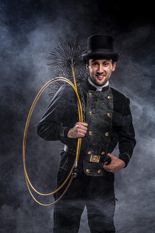 Portrait, Schornsteinfeger stehend in Arbeitskleidung mit Arbeitsgeräten