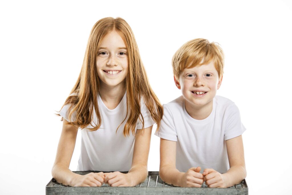 Geschwister laecheln in die kamera waehrend eines familienshootings.