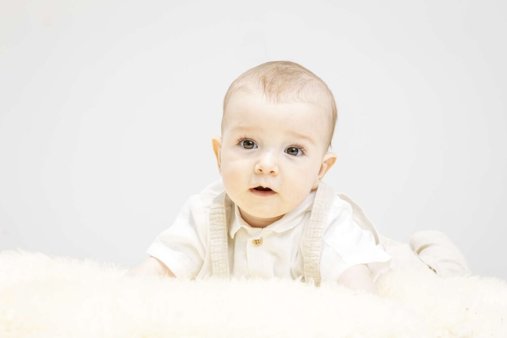 Ein laechelndes Kleinkind beim Familienshooting in einem hellen Raum.