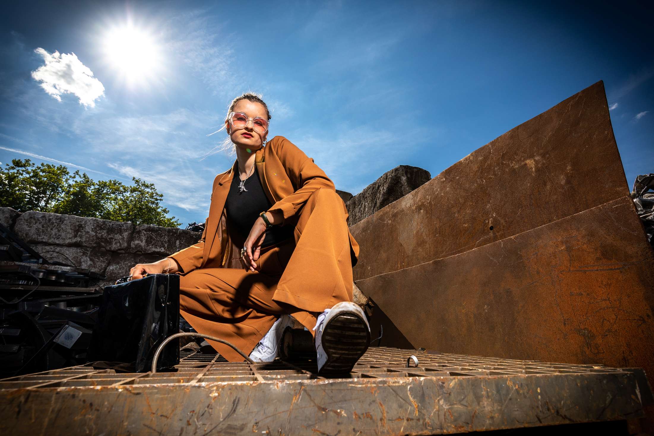 Model in braunem outfit bei einem outdoor fotoshooting im industriellen stil.