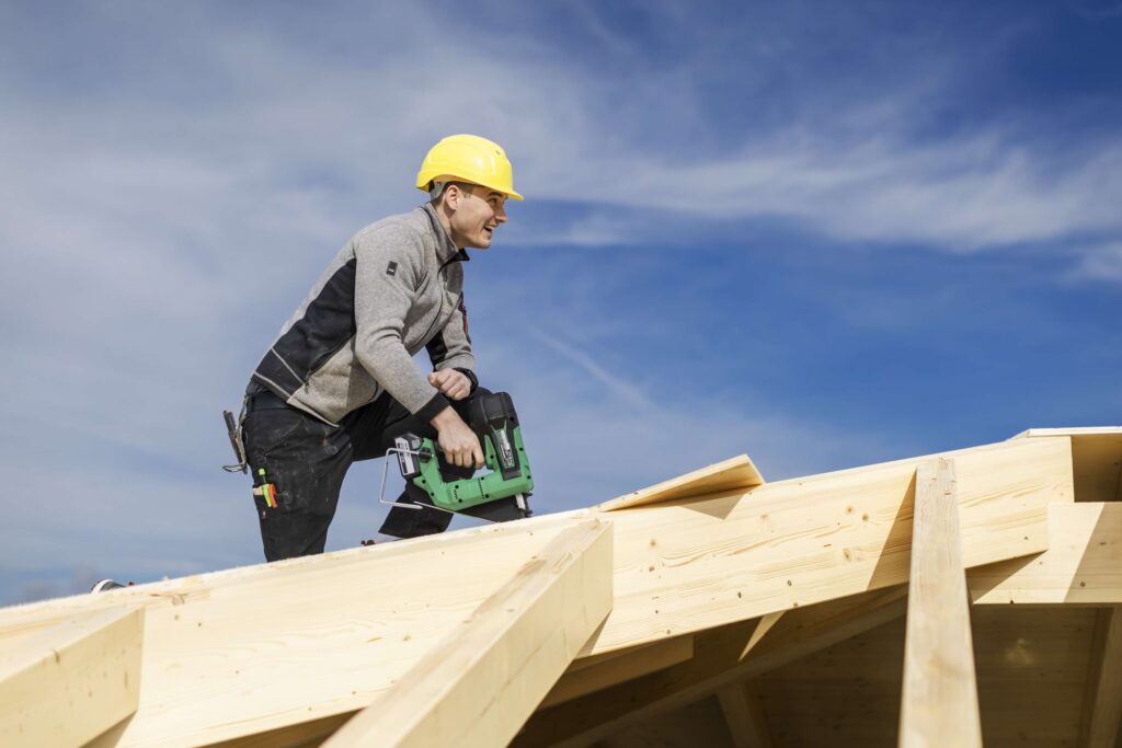 Zimmerei mitarbeiter fuehrt dacharbeiten mit einer saege durch