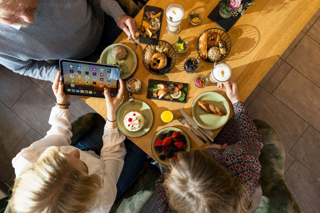 Personen an einem Tisch in einem Restaurant bestellen Essen ueber ein Tablet.