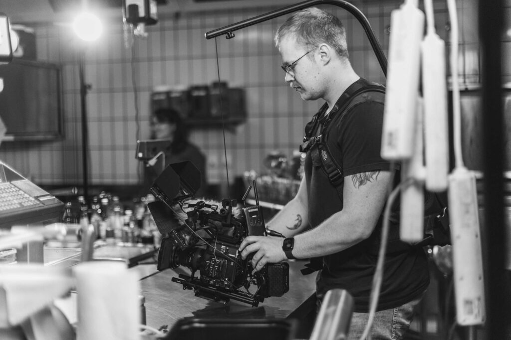 Behind the scenes eines Filmdrehs mit einem Kameramann bei der Arbeit.