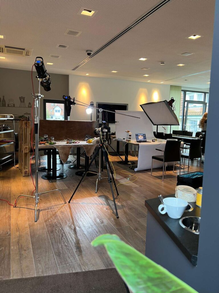 Ein Foto, das eine Szene hinter den Kulissen eines Fotoshootings zeigt, mit Kameraausruestung und Beleuchtung.