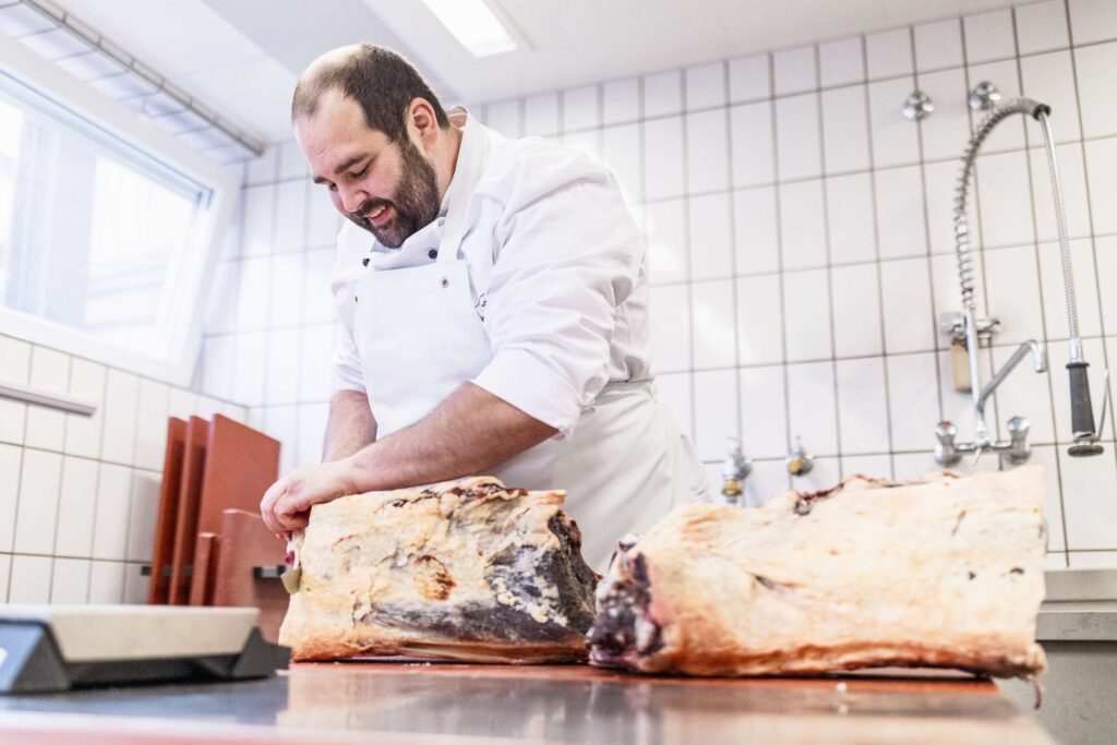 Koch bereitet Fleisch in Kueche zu