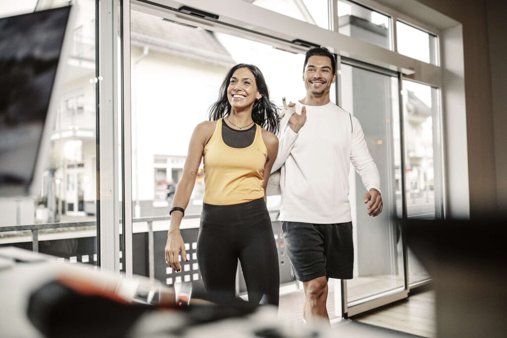 Ein Mann und eine Frau betreten freudig das Move Therapie & Training Zentrum in Kirchheim am Neckar.