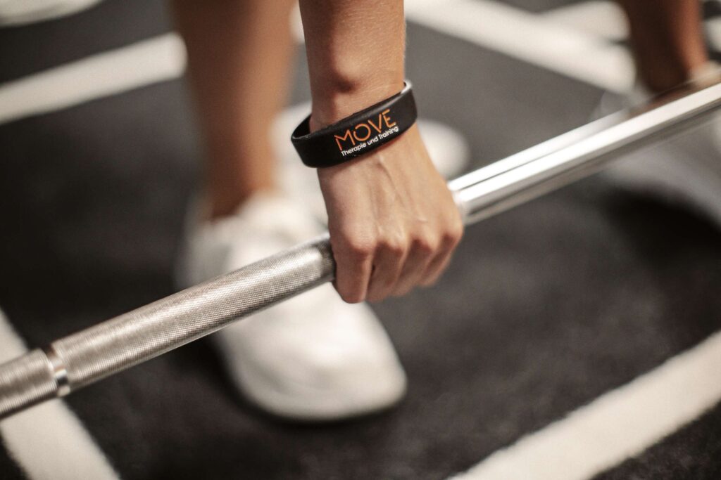 Eine Person hebt eine Hantel in einem Trainingsraum.