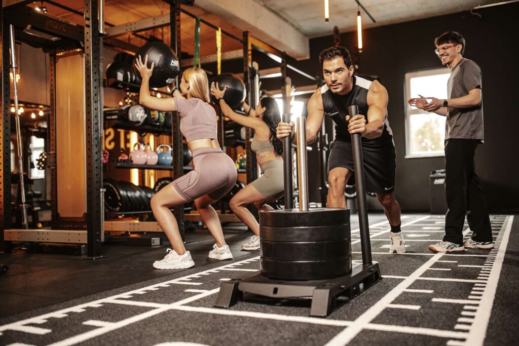 Ein Trainingsteilnehmer schiebt im Move Kirchheim Kraftgewichte, waehrend ein Trainer Anweisungen gibt.