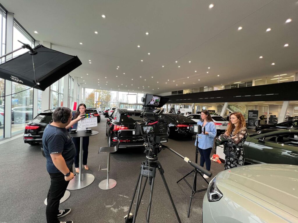 Behind the scenes eines Photoshootings in einem Autohaus mit mehreren Personen und Kameras.
