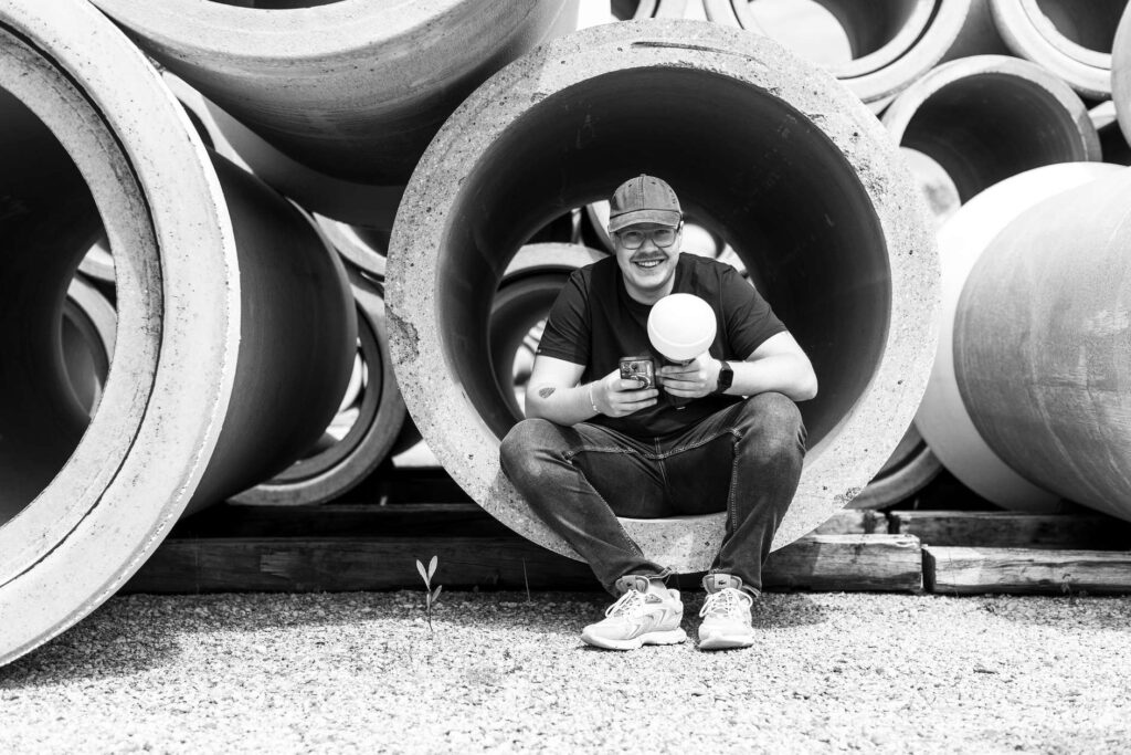 Jonas Ertle sitzt in einem großen Betonrohr und haelt eine Kamera.